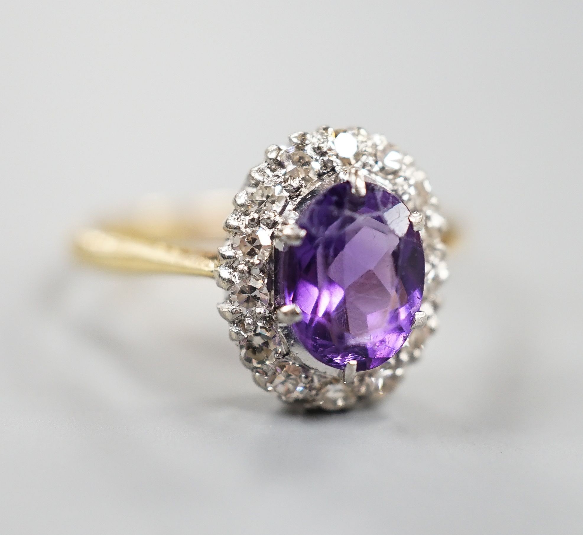 An 18ct, amethyst and diamond set oval cluster ring, size O/P, gross weight 3 grams.